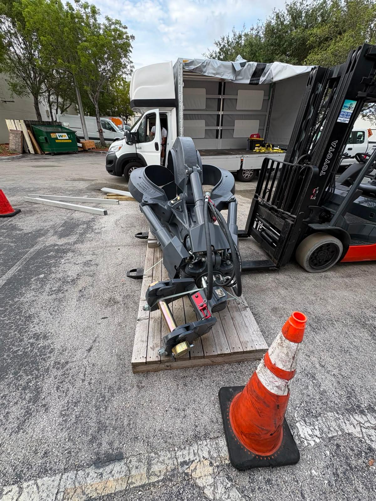 Fuchs 5-tine orange peel grapple on pallet outside the ICP Miami warehouse, Toyota forklift visible behind it