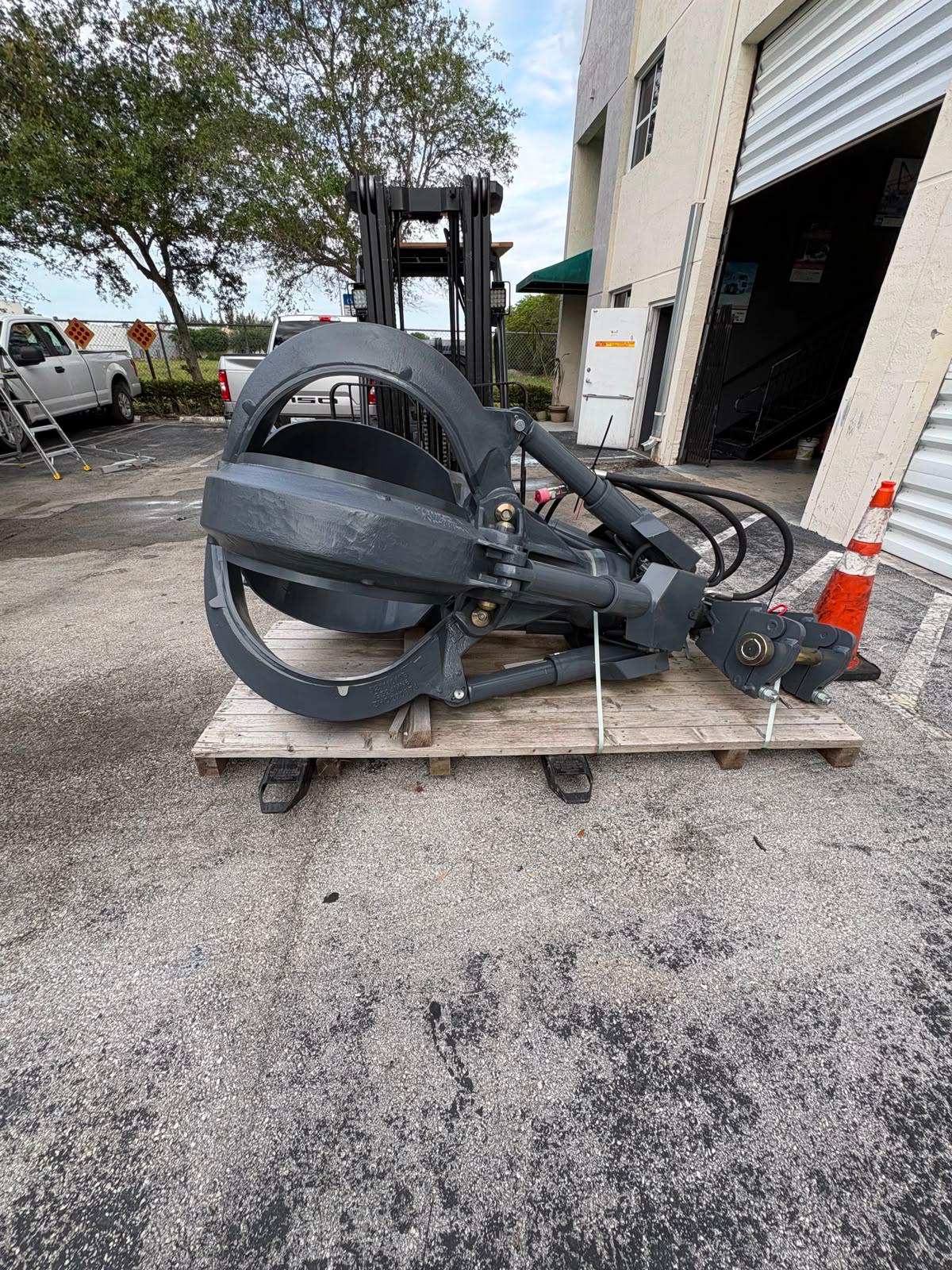 Fuchs grapple on pallet near the open rear of the export truck, being positioned for loading